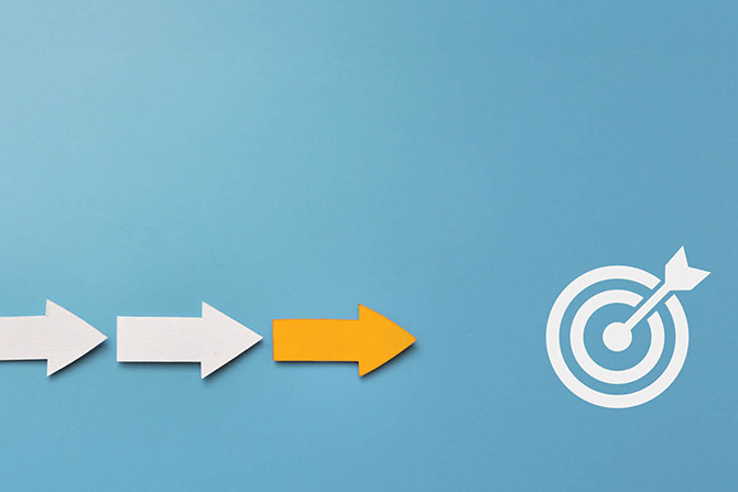 Flourish: Let’s Continue the Course in the New Year; Arrows on a blue background: two white and one yellow pointing towards a white target with an arrow in the bullseye. Symbolizes direction and achievement.